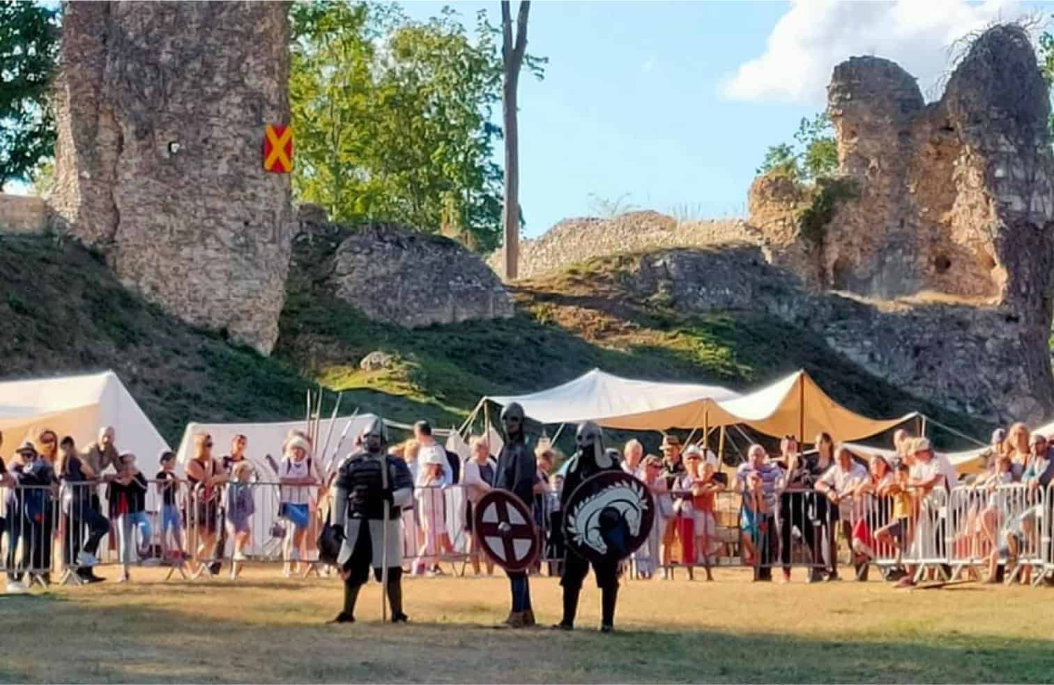 Reconstitution médiévale avec des individus blindés lors d'un festival historique en plein air.