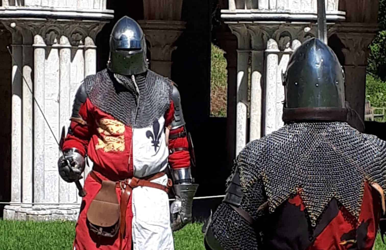 Deux individus en armure de chevalier médiéval se préparant pour une démonstration ou une reconstitution.